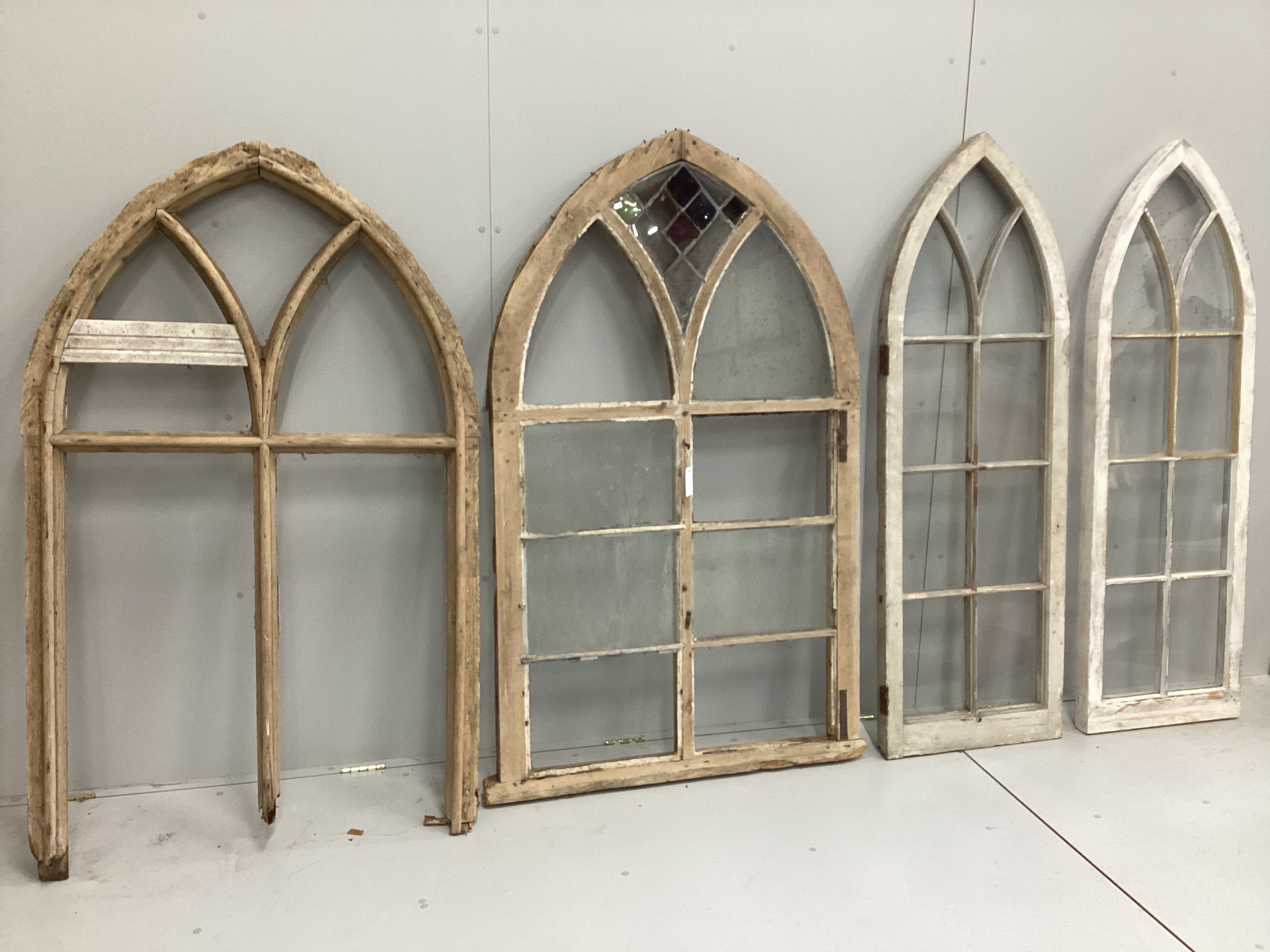 A pair of Victorian pine Gothic arched windows, one partially glazed the other with losses, width 94cm, height 158cm, and a pair of similar later windows, width 50cm, height 160cm